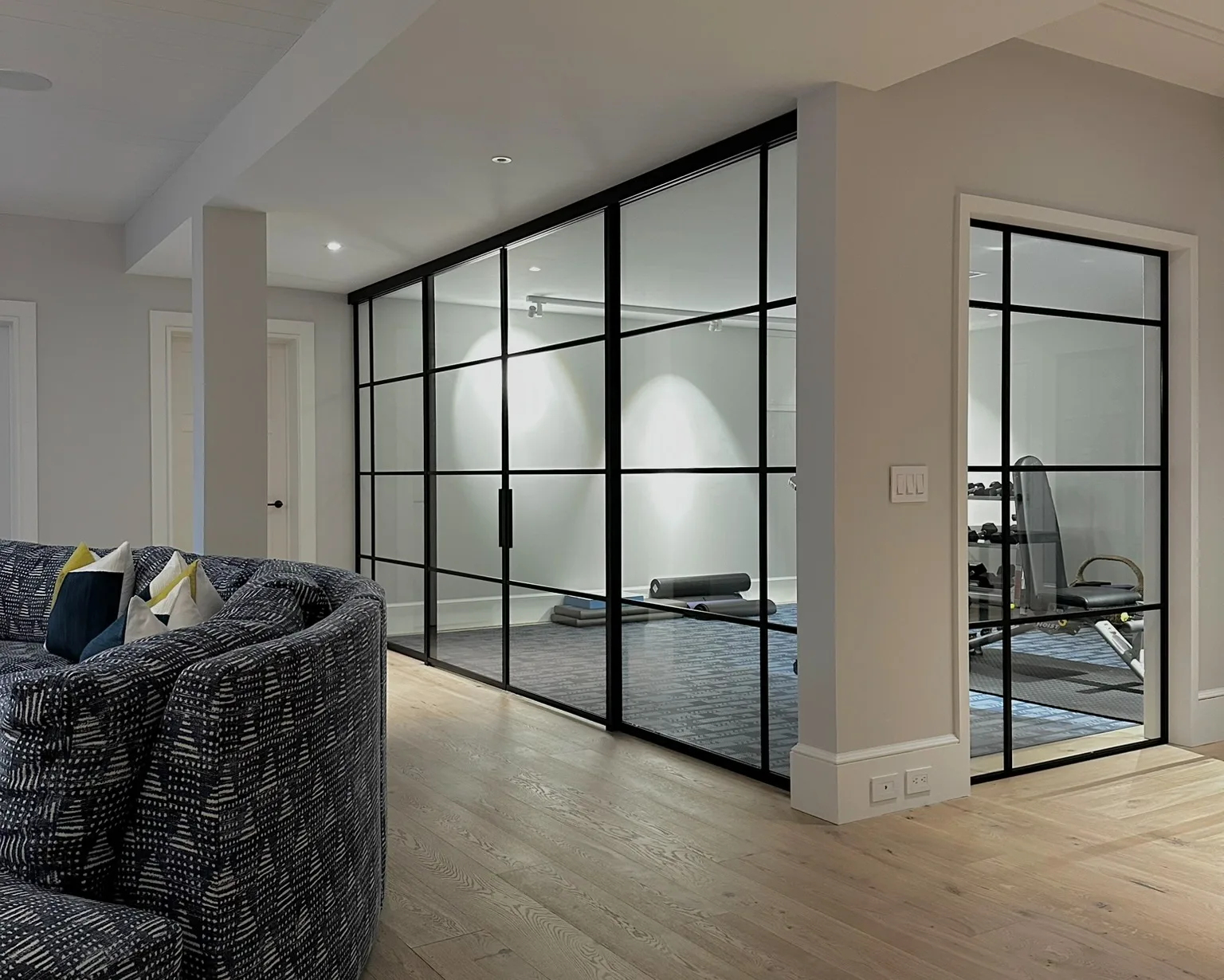 Before — open lower level of a Sagaponack NY estate, gym area exposed to living space prior to glass partition installation by WiseGlass NY