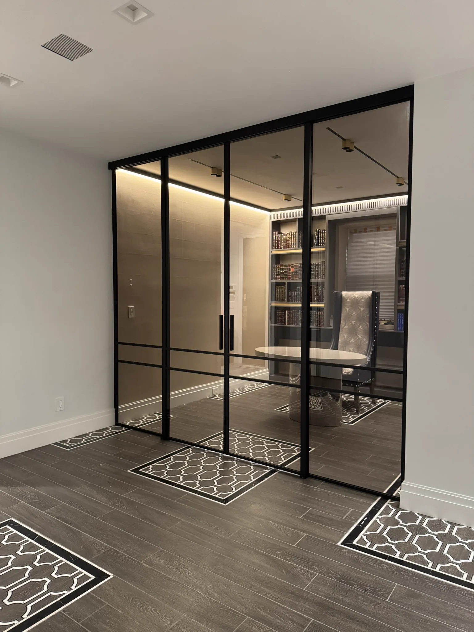Custom bronze tinted glass partition with black matte frame enclosing private library study — WiseGlass NY