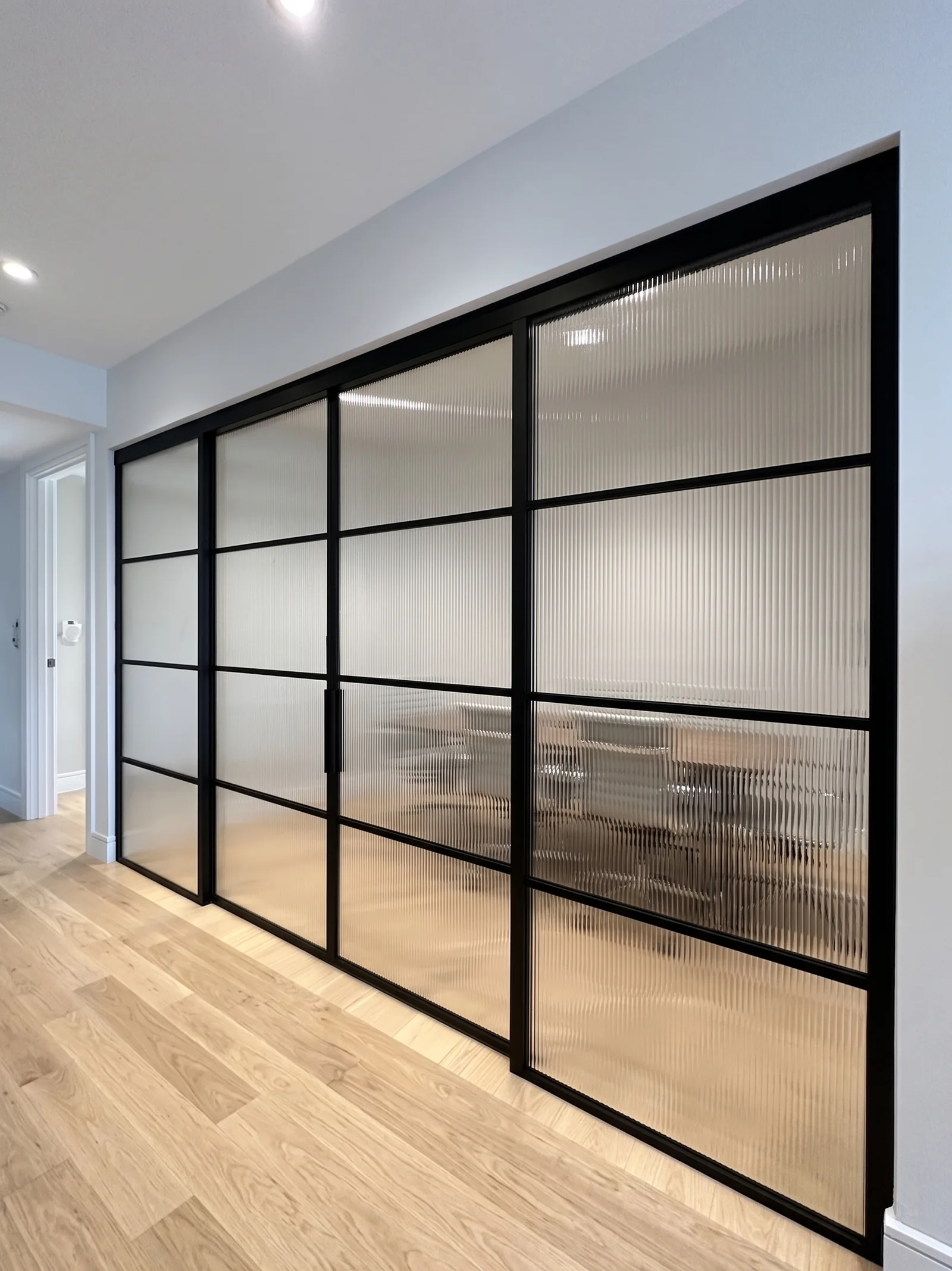 Custom reeded ribbed glass sliding partition in black matte aluminum frame — WiseGlass NY